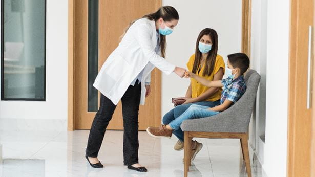a provider shaking the hand of a child in a hospital hallway