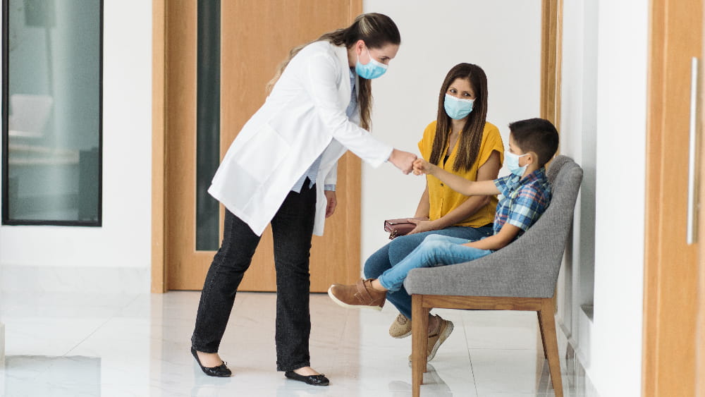 a provider shaking the hand of a child in a hospital hallway